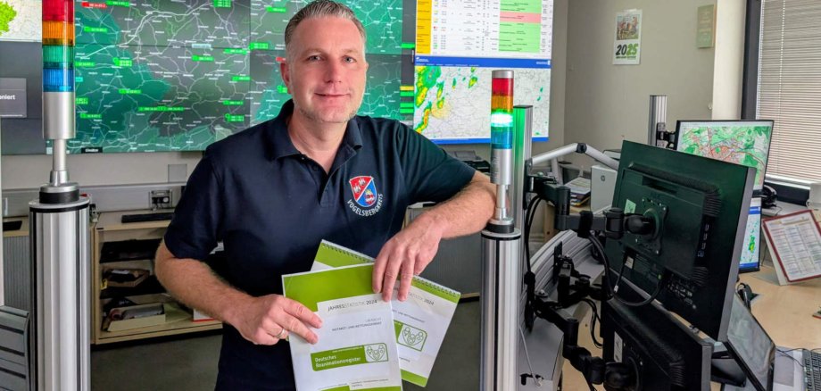 Dr. Dennis Humburg, ärztlicher Leiter des Rettungsdiensts im Vogelsbergkreis, präsentiert die Daten des Reanimations-Register für den Vogelsbergkreis. Er steht vor einer Videowand, an der Rettungsdienstinformationen und KArten zu sehen sind.