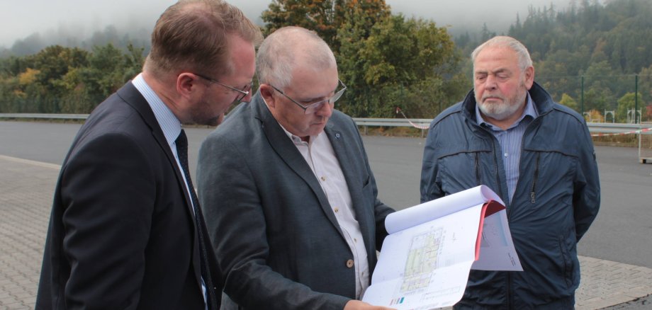 Erster Kreisbeigeordneter Dr. Jens Mischak (links) und Schlitz Erster Stadtrat Willy Kreuzer lassen sich von Uwe Heinbach, Betriebsstättenleiter der Online Systemlogistik GmbH & Co. KG, die Pläne für den Neubau des Büro- und Sozialgebäudes erläutern.                           