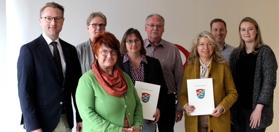 Eine Gruppe von Menschen steht vor einer weißen Fotowand. 