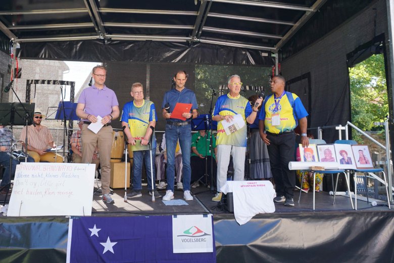 Gemeinsame Eröffnung des Inklusiven Sportfests: Dr. Jens Mischak, Erster Kreisbeigeordneter, gemeinsam mit Hans Jürgen Röhr, kommunaler Behindertenbeauftragter, Holger Marx, 1. Stadtrat der Kreisstadt Lauterbach, Dolmetscher John Pachen, und Enrico Viscaȉno von der Delegation bei der Eröffnung. Sie stehen auf einer Bühne und halten eine Rede.