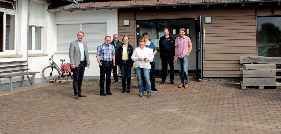 Der Erste Kreisbeigeordnete Dr. Jens Mischak (links) übergibt gemeinsam mit Angelika Boese (Vierte von links), Sachgebietsleitung Dorf- und Regionalentwicklung, Amt für Wirtschaft und den ländlichen Raum, den Bescheid für das „Dörfergemeinschaftshaus Moosbachtal“ an Bürgermeister Sebastian Stang (von links), Martin Oechler, Mitglied im Gemeindevorstand, Gabriele Koenig, Ortsvorsteherin von Metzlos-Gehaag, Simone König-Müller, Ortsvorsteherin von Metzlos, Stefan Weitzel, Fraktionsvorsitzender in der Gemeindevertretung, und Klaus Bestvater, Mitglied im Gemeindevorstand.