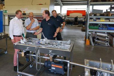 Jan Herchenröder (rechts, vorne), Techniker bei Boss Vakuum, und Thorsten Schindler, Produktionsleiter bei Boss Vakuum, erläutern Dr. Jens Mischak (Zweiter von links), Erster Kreisbeigeordneter, und Bernhard Ziegler, Bürgermeister der Stadt Herbstein, die Funktionsweise einer Vakuummaschine.