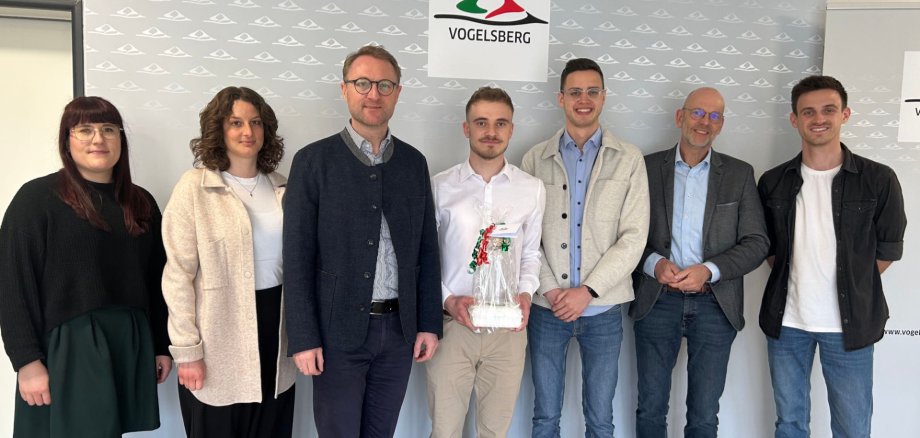 Hervorragende Leistung: Elias Christen (Mitte) hat sein BASS-Studium erfolgreich abgeschlossen und nimmt die Glückwünsche von Landrat Dr. Jens Mischak (Dritter von links), Hauptamtsleiter Ulrich Schäfer (Zweiter von rechts), Ausbildungsleiter Timo Walper (rechts), seinem Fachdienstleiter bei der KVA, Florian Steuernagel (Dritter von rechts), der Ausbildungsleiterin der BASS-Studenten, Lisa Schlitt (Zweite von links) und der Gleichstellungsbeauftragten Antonia Schäfer entgegen.