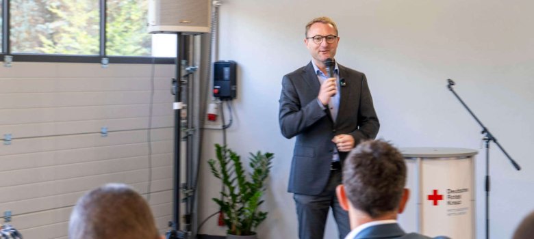 Landrat Dr. Mischak hält ein Mikrofon und spricht zu Gästen