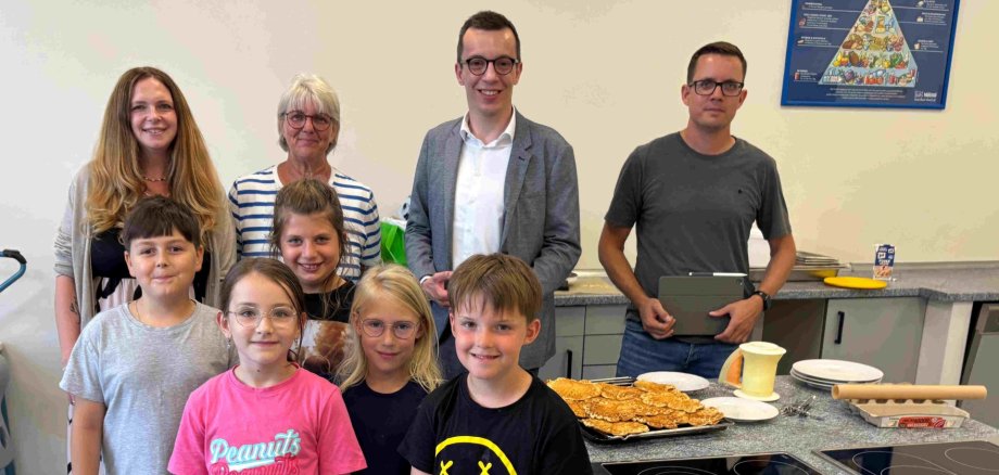 Erster Kreisbeigeordneter und Schuldezernent Patrick Krug (zweiter von rechts) besucht gemeinsam mit Florian Eurich (rechts), stellvertretender Leiter des Amts für Schulische Bildung und Betreuung, die Ferienbetreuung an der Grundschule Feldatal. Dort werden die beiden von Denise Steuernagel-Mahr (hinten, von links) und Martina Seibert vom Betreuungsteam sowie von David, Thea, Emma, Clara und Maximilian empfangen.