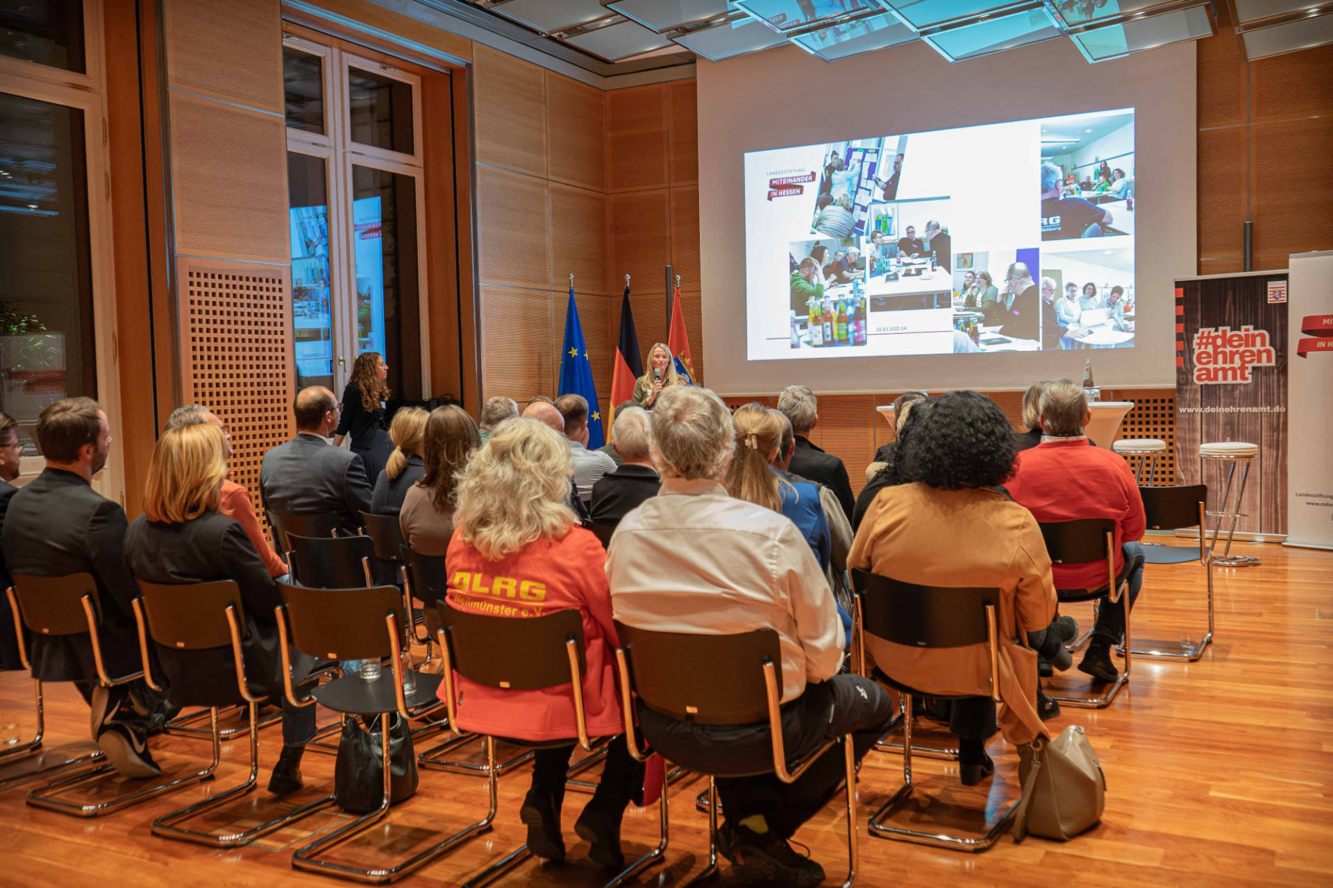 Rund 50 Personen sitzen in einem Veranstaltungsraum und hören einem Vortrag zu
