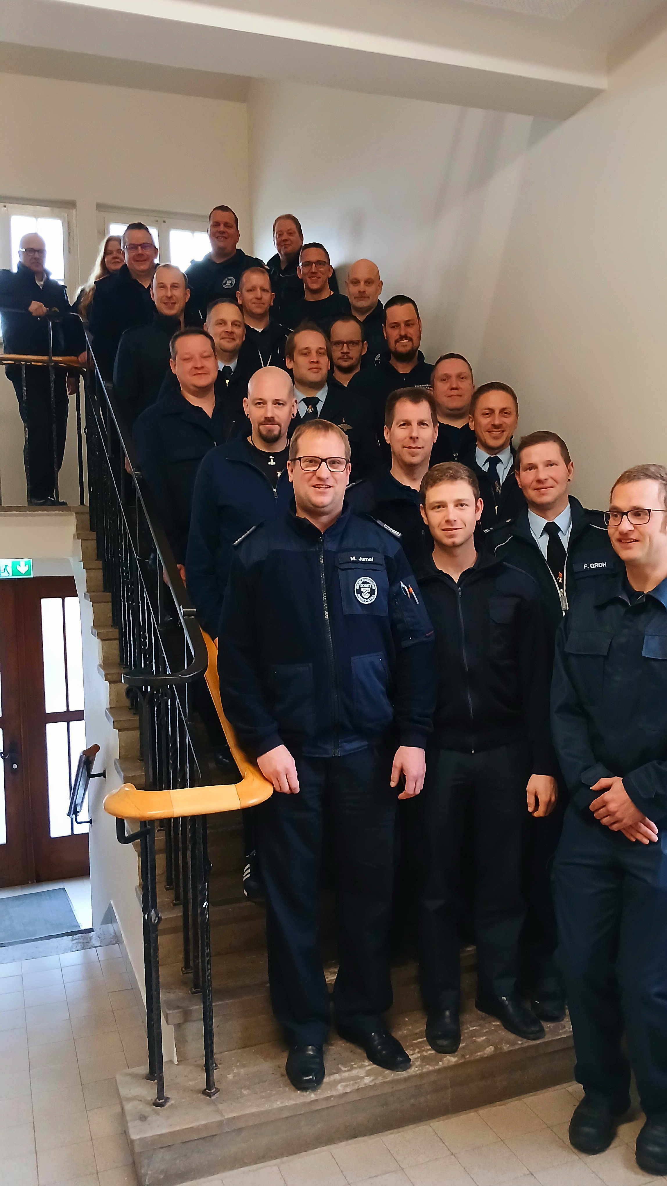 Rund 20 Personen in Feuerwehruniform haben sich auf einer Treppe zum Gruppenbild aufgestellt
