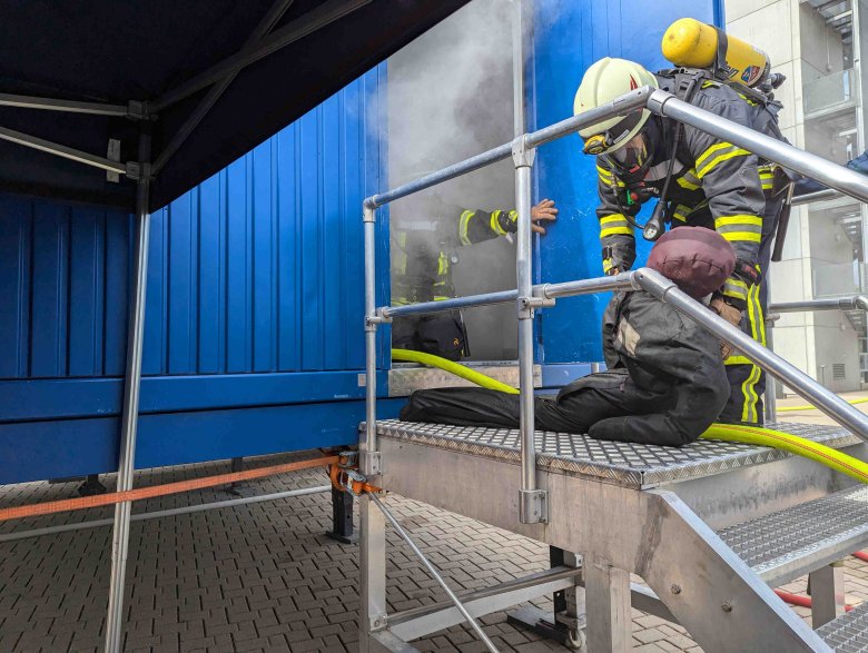 zwei Feuerwehrleute ziehen einen Dummy aus einer verrauchten Simulationsanlage