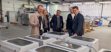 Fünf Menschen stehen an einem Schaltschrank aus Glasfaserverstärktem Kunststoff.