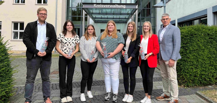 Geschafft! Landrat Manfred Görig gratuliert Marie Vaupel, Annika Goll, Sarah Kuhla, Cora Weiß, Alina Warkentin und Patrick Döring (von rechts) zu ihren Super-Ergebnissen bei den Abschlussprüfungen. Sie haben sich zum Gruppenbild vor dem Haupteingang der Kreisverwaltung aufgestellt.