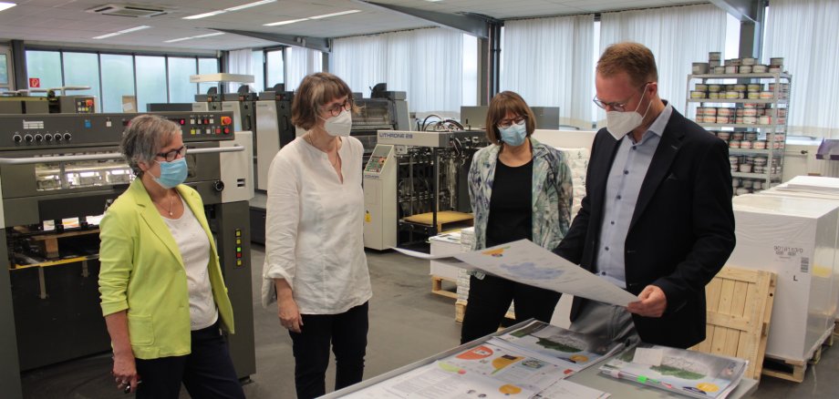 Der Erste Kreisbeigeordnete Dr. Jens Mischak (CDU, rechts), wirft gemeinsam mit Monika Schenker (von rechts), Leiterin des Amtes für Volkshochschule, Petra Dörr-Eisenträger, von der Lauterbacher Druckerei Mergard, und Karin Gröger, stellvertretende Amtsleiterin und Fachbereichsleitung Gesundheit und Gesellschaft einen Blick auf die Konzeption und erste Druckbögen.
