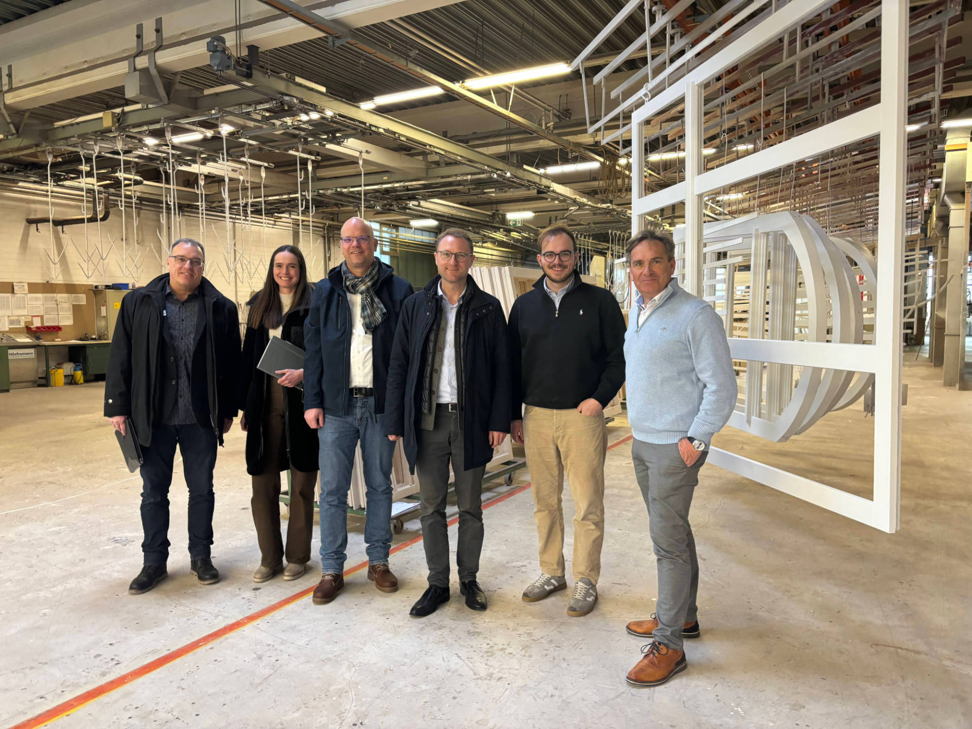 Landrat und Wirtschaftsdezernent Dr. Jens Mischak (dritter von rechts), gemeinsam mit Reiner Dräger (von rechts), zuständig für den Vertrieb bei FR Frame Fenstersysteme, dem geschäftsführenden Gesellschafter Fabian Dräger, dem Bürgermeister von Wartenberg, Dr. Olaf Dahlmann, sowie Kathrin Janisch von der Wirtschaftsförderung und Jens Pietsch, vom Arbeitgeberservice der KVA – Kommunales Jobcenter des Vogelsbergkreises, beim Rundgang durch die Produktion.