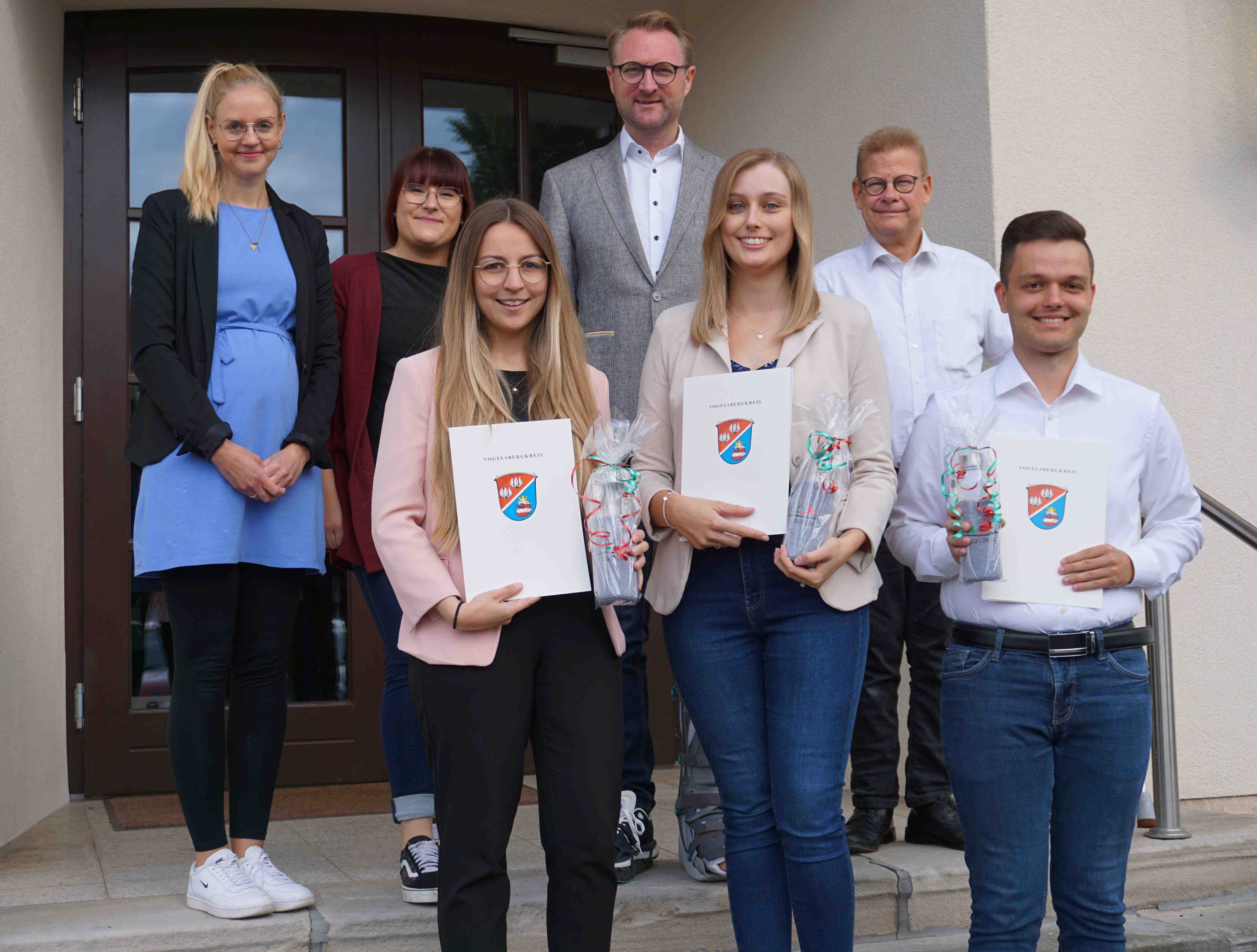 Erster Kreisbeigeordneter Dr. Jens Mischak (hinten, Mitte), mit Anna-Lena Kleinschmidt (Freiensteinau, vorne, von links), Annalena Lang (Lautertal, von rechts), und Florian Paloh (Feldatal), sowie Ausbildungsleiterin Ann-Kathrin Ruhl (hinten, von links), Antonia Schäfer, stellvertretende Frauenbeauftragte, und Hans-Jürgen Röhr vom Personalrat, beim Gruppenbild vor dem alten Haupteingang der Lauterbacher Kreisverwaltung.