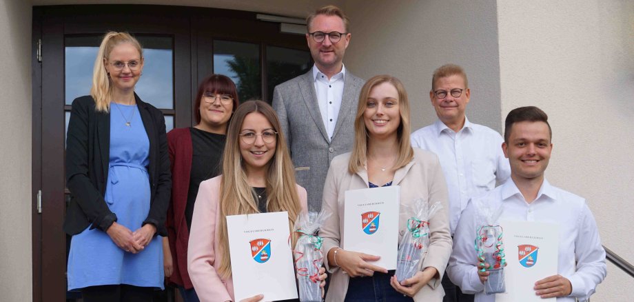 Erster Kreisbeigeordneter Dr. Jens Mischak (hinten, Mitte), mit Anna-Lena Kleinschmidt (Freiensteinau, vorne, von links), Annalena Lang (Lautertal, von rechts), und Florian Paloh (Feldatal), sowie Ausbildungsleiterin Ann-Kathrin Ruhl (hinten, von links), Antonia Schäfer, stellvertretende Frauenbeauftragte, und Hans-Jürgen Röhr vom Personalrat, beim Gruppenbild vor dem alten Haupteingang der Lauterbacher Kreisverwaltung.