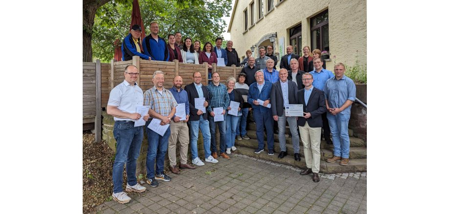 Dr. Jens Mischak (vorne, Zweiter von rechts), Vorstandsvorsitzender des Vereins Region Vogelsberg, und Edwin Schneider (Dritter von rechts), Vorsitzender des LEADER-Beirats, gemeinsam mit Vertreterinnen und Vertretern der Vereine und Kommunen sowie des LEADER-Regionalmanagements bei der Übergabe der Zuwendungsverträge an der Turnhalle Frischborn.