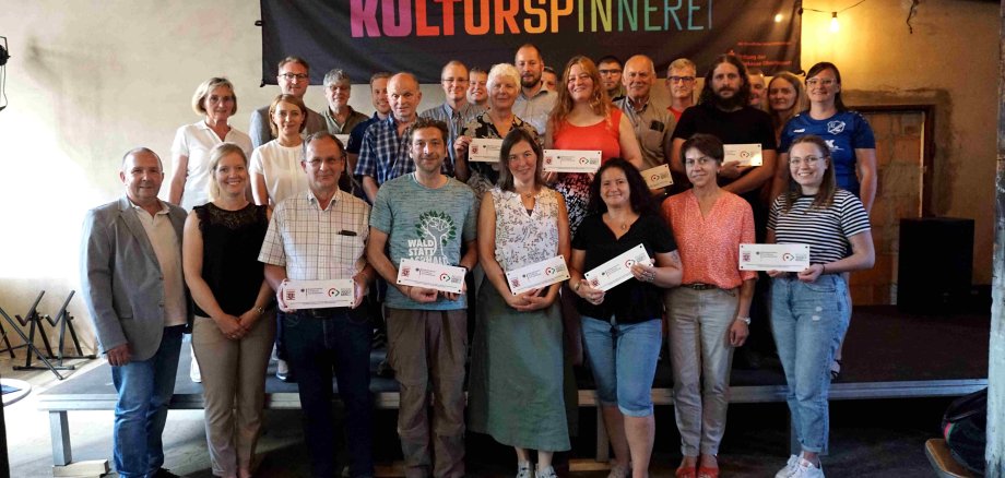  Die Plaketten, die bares Geld wert sind: Dr. Jens Mischak (hintere Reihe links), gemeinsam mit den Vertreterinnen und Vertretern Vogelsberger Vereine, die in der Lauterbacher Kulturspinnerei die Regionalbudget-Plaketten präsentieren. Zuständig für Beratung und Vergabe sind Matthias Steckenreuther (vorne von links), Jennifer Berger, Verein Region Vogelsberg, Christel Hensel (zweite Reihe von links), stellvertretende Vorsitzende des LEADER-Entscheidungsgremiums sowie Tatjana Heinz vom Verein Region Vogelsberg. 