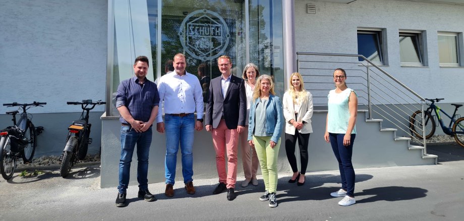 Sieben Menschen haben sich vor einem Gebäudeeingang zum Gruppenbild aufgestellt. Dr. Jens Mischak (Dritter von links), Erster Kreisbeigeordneter und Wirtschaftsdezernent, gemeinsam mit Betriebsleiter und Prokurist Samuel Hess (von links), Geschäftsführer Kai Kloske, Andrea Ortstadt von der Wirtschaftsförderung, Susanne Schaab, Bürgermeisterin der Stadt Schotten, Annabel Ziepf, Kaufmännischen Leiterin und Prokuristin bei Schüth sowie Susen Neumann, Arbeitgeberservice der KVA Vogelsbergkreis sind darauf zu sehen.