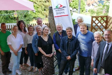 Menschen haben sich in einem Biergarten zum Gruppenfoto aufgestellt.