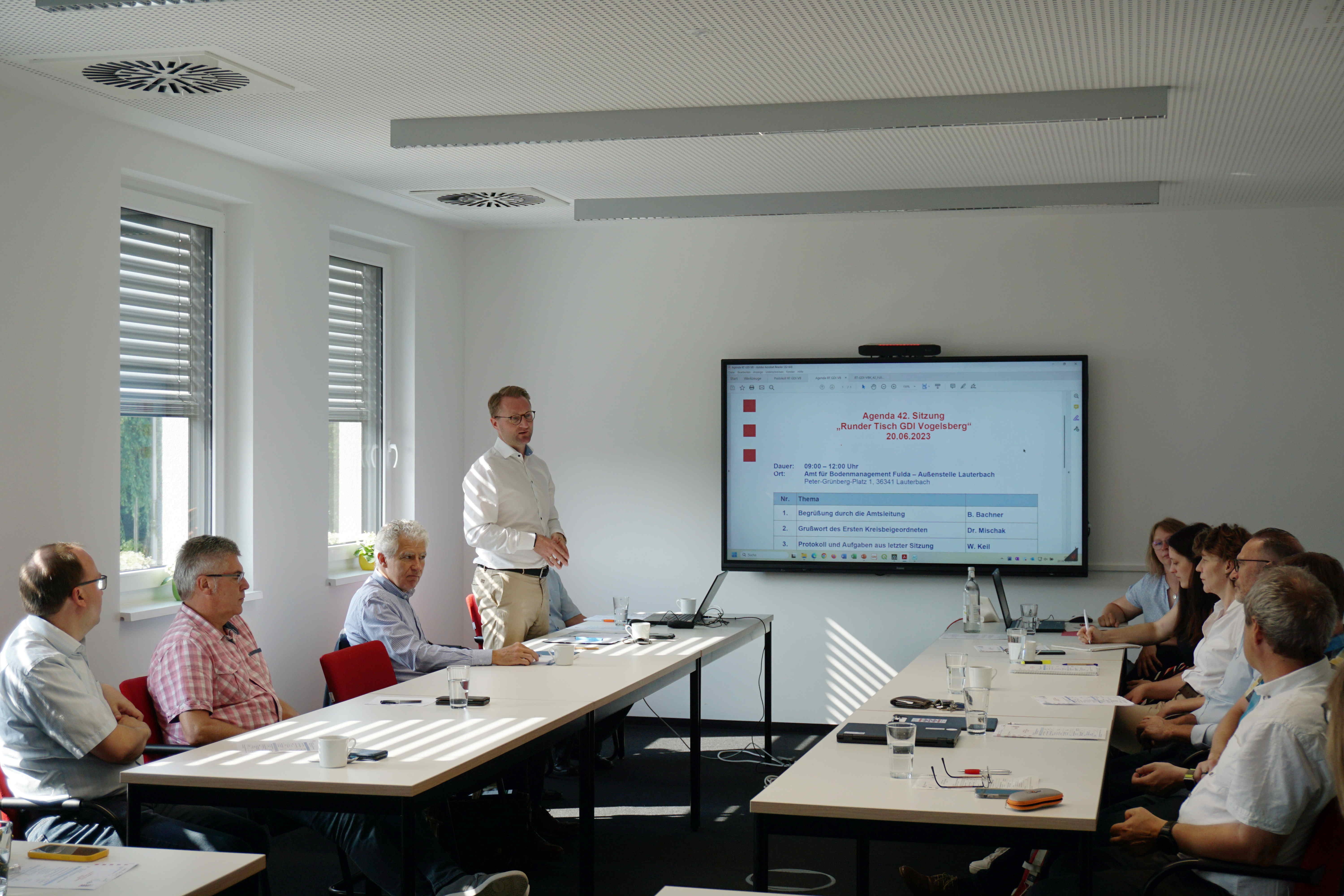 Dr. Jens Mischak (stehend), Erster Kreisbeigeordneter und Baudezernent, begrüßt die Teilnehmerinnen und Teilnehmer des „Runden Tisches Geodateninfrastruktur (GDI) Vogelsberg“ im Amt für Bodenmanagement Fulda, Außenstelle Lauterbach. In seinem Grußwort hebt er besonders die gute Zusammenarbeit zwischen dem Amt für Bodenmanagement, dem Regierungspräsidium, den Städten und Gemeinden sowie dem Kreis hervor.
