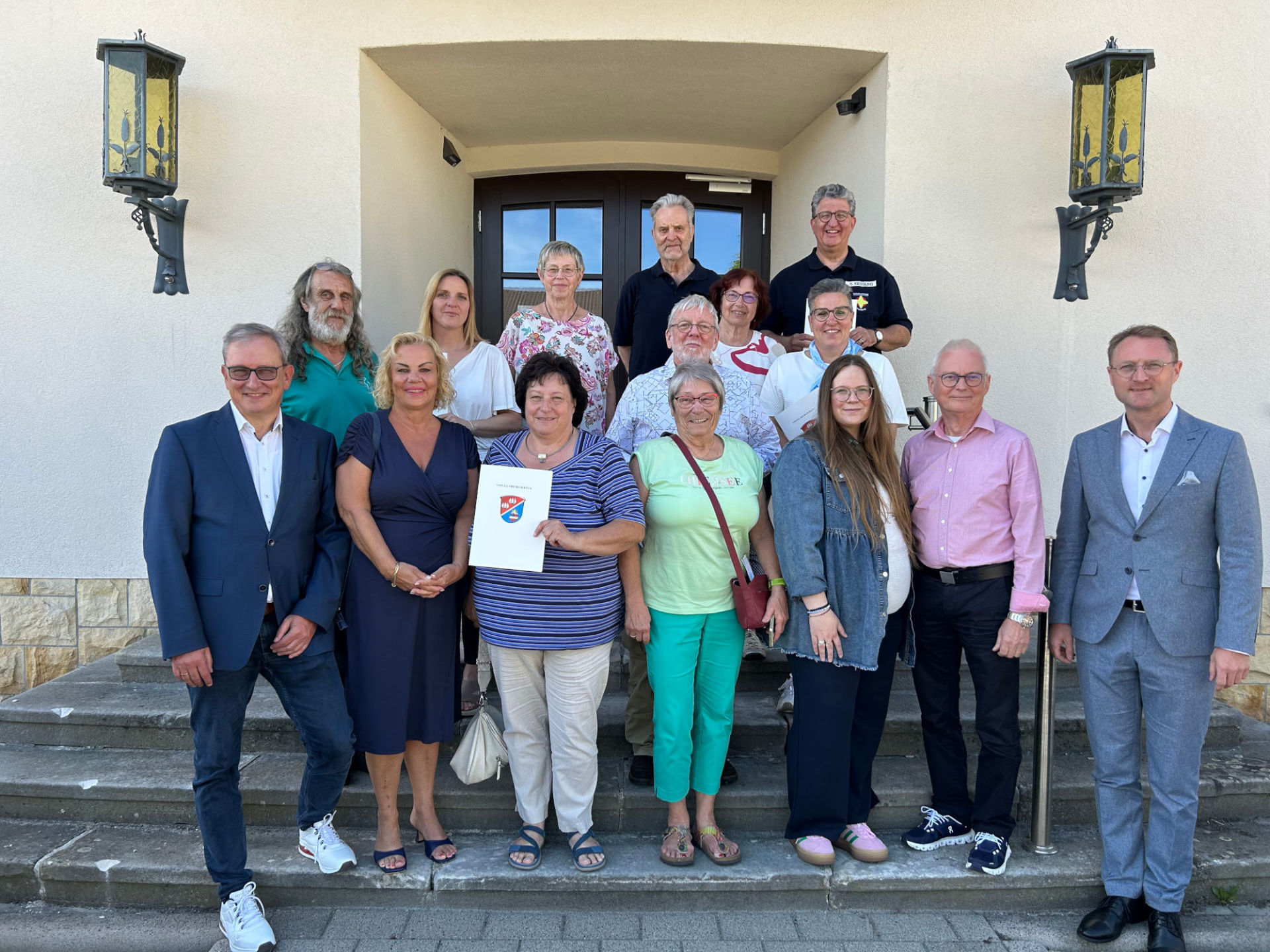 Knapp 15 Personen haben sich auf einer Treppe für ein Gruppenfoto aufgestellt.
