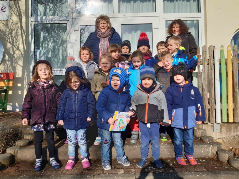 Eine Gruppe Kindergartenkinder mit zwei Erzieherinnen aufgestellt zum Gruppenbild