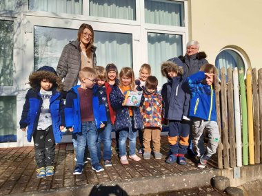 Eine Gruppe Kindergartenkinder mit zwei Erzieherinnen aufgestellt zum Gruppenbild