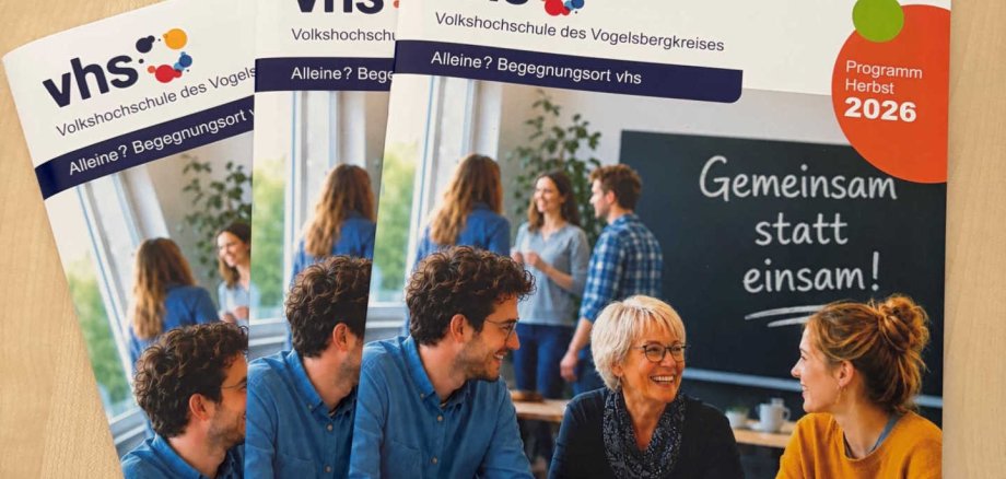 Drei Programmhefte liegen auf einem Tisch.