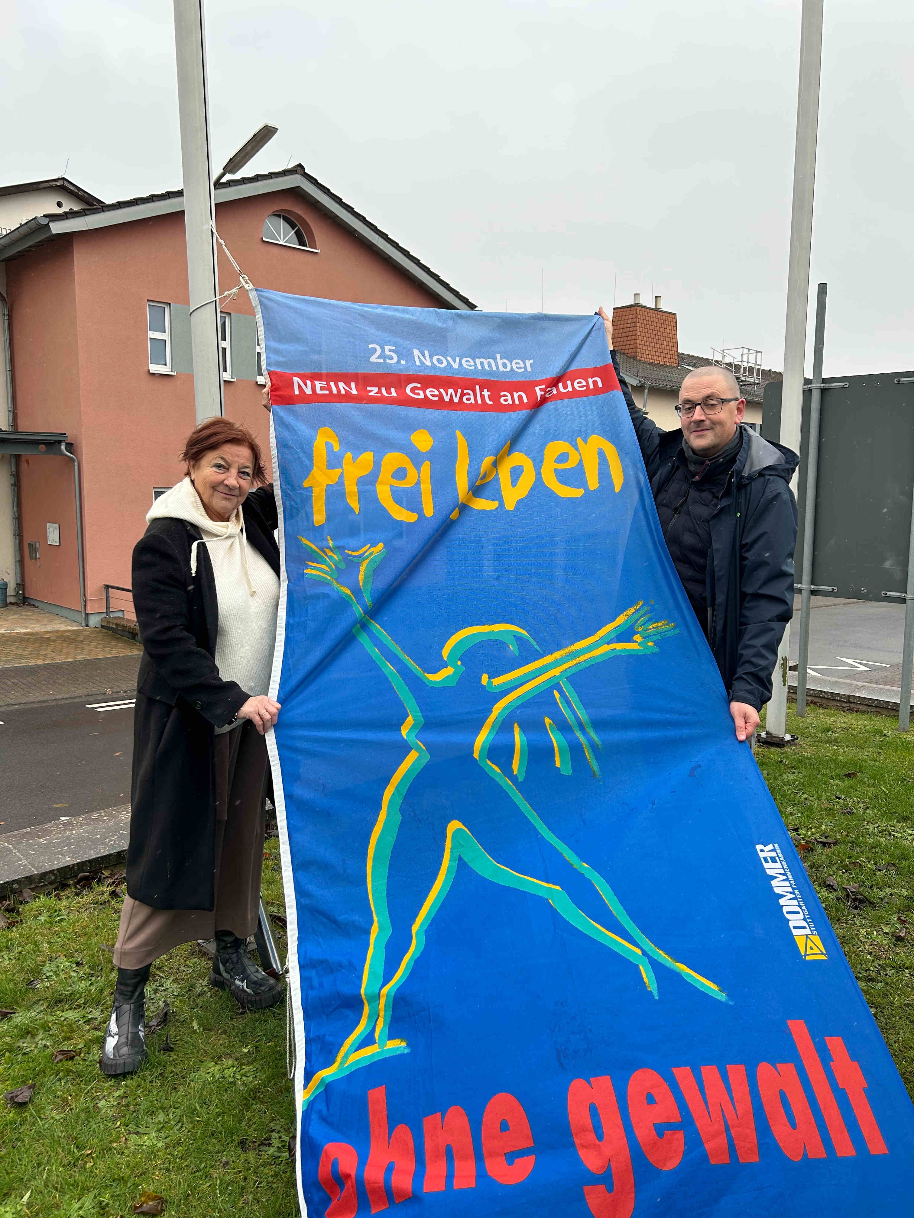 Elisabeth Hillebrand, Beauftragte für Integration und Gleichstellung, gemeinsam mit Bastian Heck, Leiter des Sachgebiets Soziale Dienste im Amt für Soziales und Ausländerrecht, mit der Fahne des Vereins „Terre des Femmes“, die unter dem Motto „NEIN zu Gewalt an Frauen! – Frei leben ohne Gewalt“ auf den internationalen Tag gegen Gewalt an Frauen aufmerksam macht.