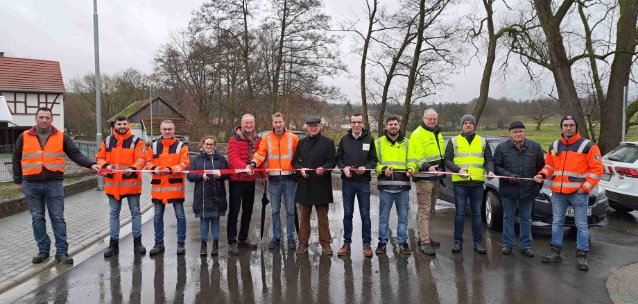 Der Erste Kreisbeigeordnete des Vogelsbergkreises, Patrick Krug (Sechster von rechts), Mückes Bürgermeister Andreas Sommer (Siebter von rechts) und weitere Vertreter von Hessen Mobil, Kreis, Gemeinde und Baufirma beim Moment der offiziellen Verkehrsfreigabe an der K 140 in Ilsdorf.