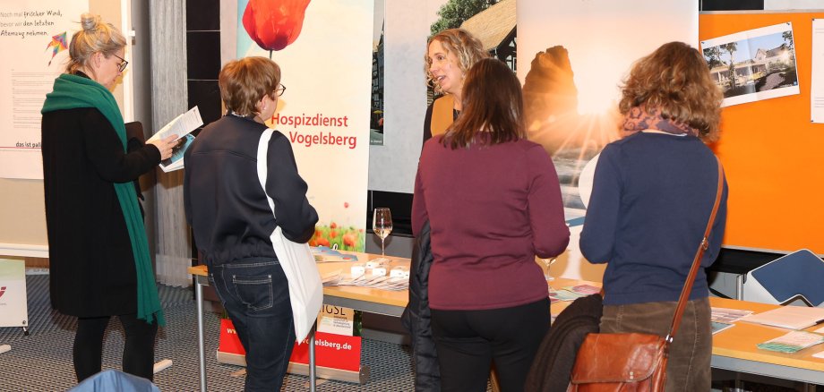Fünf Frauen sprechen an einem Informationsstand über das Thema Hospiz- und Palliativversorgung.