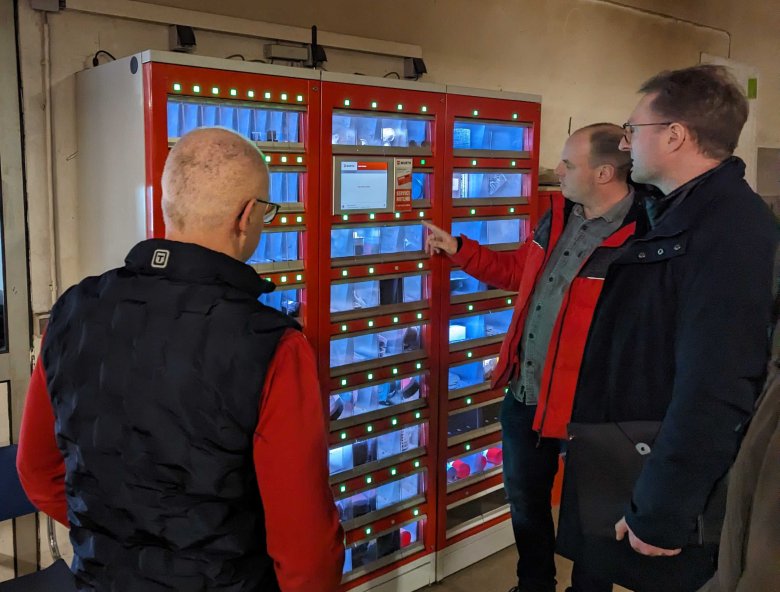 Norman Schneider (Mitte) erklärt das automatisierte Lager für Verbrauchsmaterial. Gehen beispielsweise die Bohrer zur Neige, fordert das System automatisch Nachschub an.