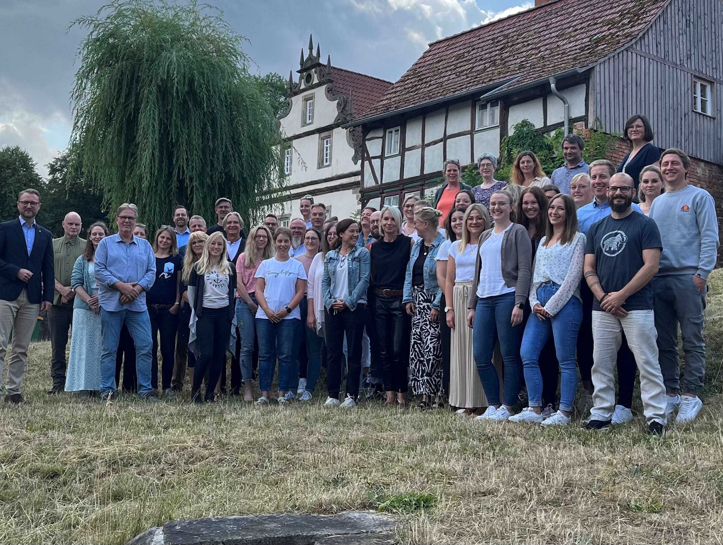 etwa 30 Menschen haben sich zu einem Gruppenbild vor einem Fachwerkhaus aufgestellt