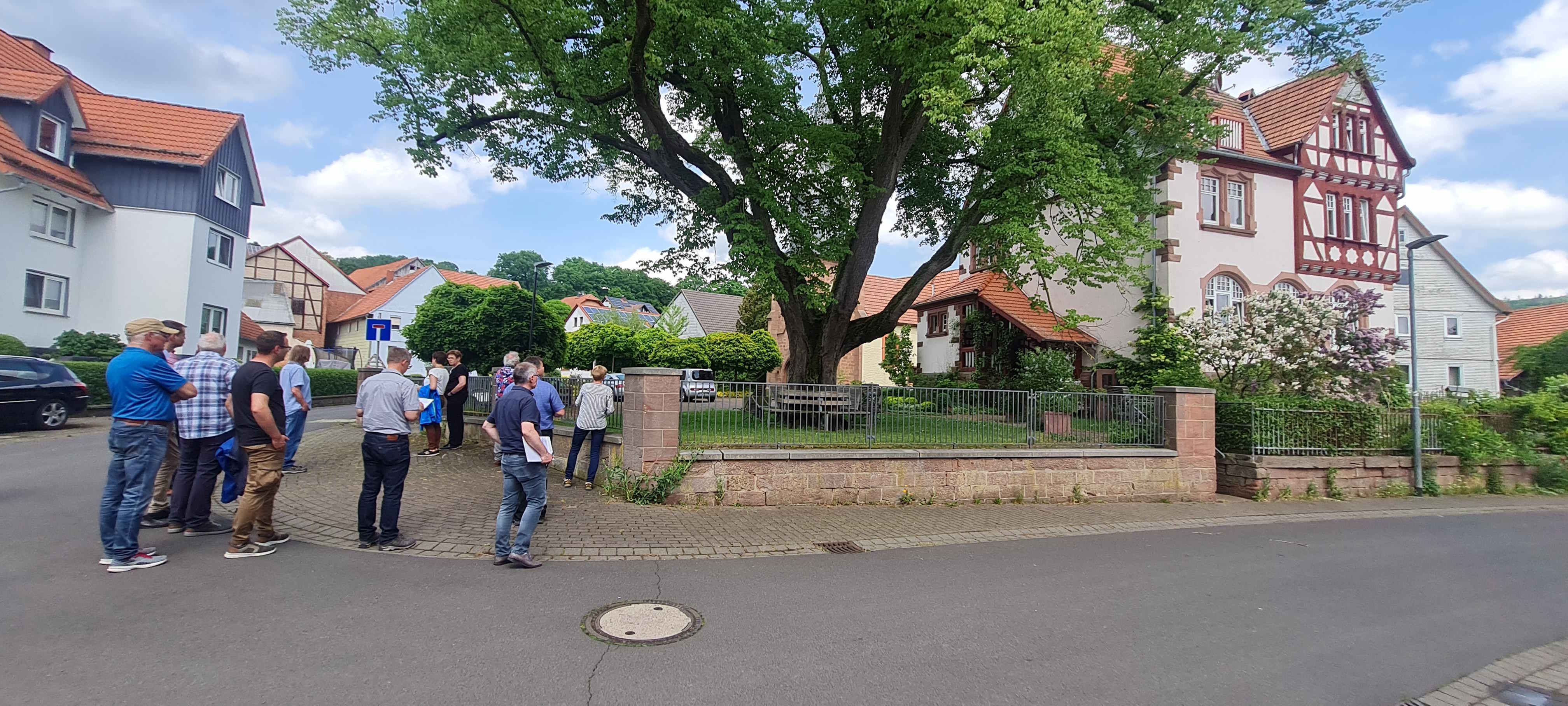 Archivbild von der Jury-Bereisung aus Pfordt. Der Schlitzer Stadtteil nahm beim 37. Wettbewerb als eines von 12 hessischen Dörfern am Landesentscheid teil. Eine Gruppe von Menschen steht an einem Grundstück mit einem imposanten alten Baum im Vorgarten