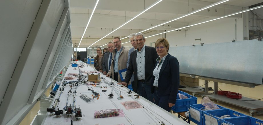 Ein Kabelbaum in der Entstehung: Dr. Jens Mischak (Mitte), Erster Kreisbeigeordneter, beim von Andrea und Andreas Reichhardt, Geschäftsführer, geführten Rundgang durch den Unternehmensstandort. Auch Lorenz Kock, Sachgebietsleiter Wirtschaftsförderung, Dieter Schäfer, Bürgermeister der Gemeinde Lautertal, Laura Refflinghaus, Wirtschaftsförderung, und Susen Neumann, KVA Vogelsbergkreis - Kommunales Jobcenter, machen sich ein Bild vom Standort.