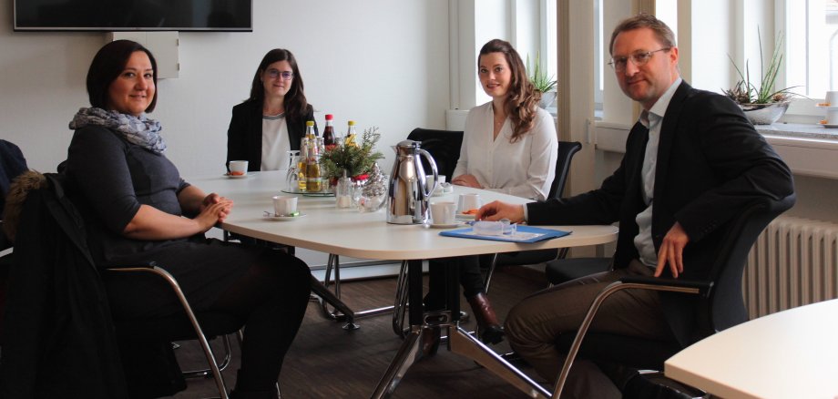 Vier PErsonen sitzen an einem großen Tisch und schauen in die Kamera. Sie lächeln. Der Erste Kreisbeigeordnete Dr. Jens Mischak (rechts) und Carina Diezemann von der Fachstelle Gesundheitliche Versorgung (Zweite von links), im Gespräch mit den neuen Stipendiatinnen Olga Kappel (links) und Lara Marie Liebler. Beide möchten in Zukunft als Fachärztinnen für Allgemeinmedizin im Vogelsbergkreis arbeiten. (Foto: Vogelsbergkreis C.Lips)