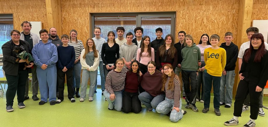 Rund 20 Menschen haben sich in einem Sitzungsraum zu einem Gruppenbild aufgestellt.