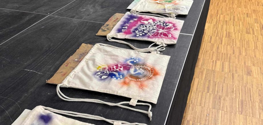 Kunstvoll verzierte Turnbeutel liegen auf einer kleinen Bühne aus.