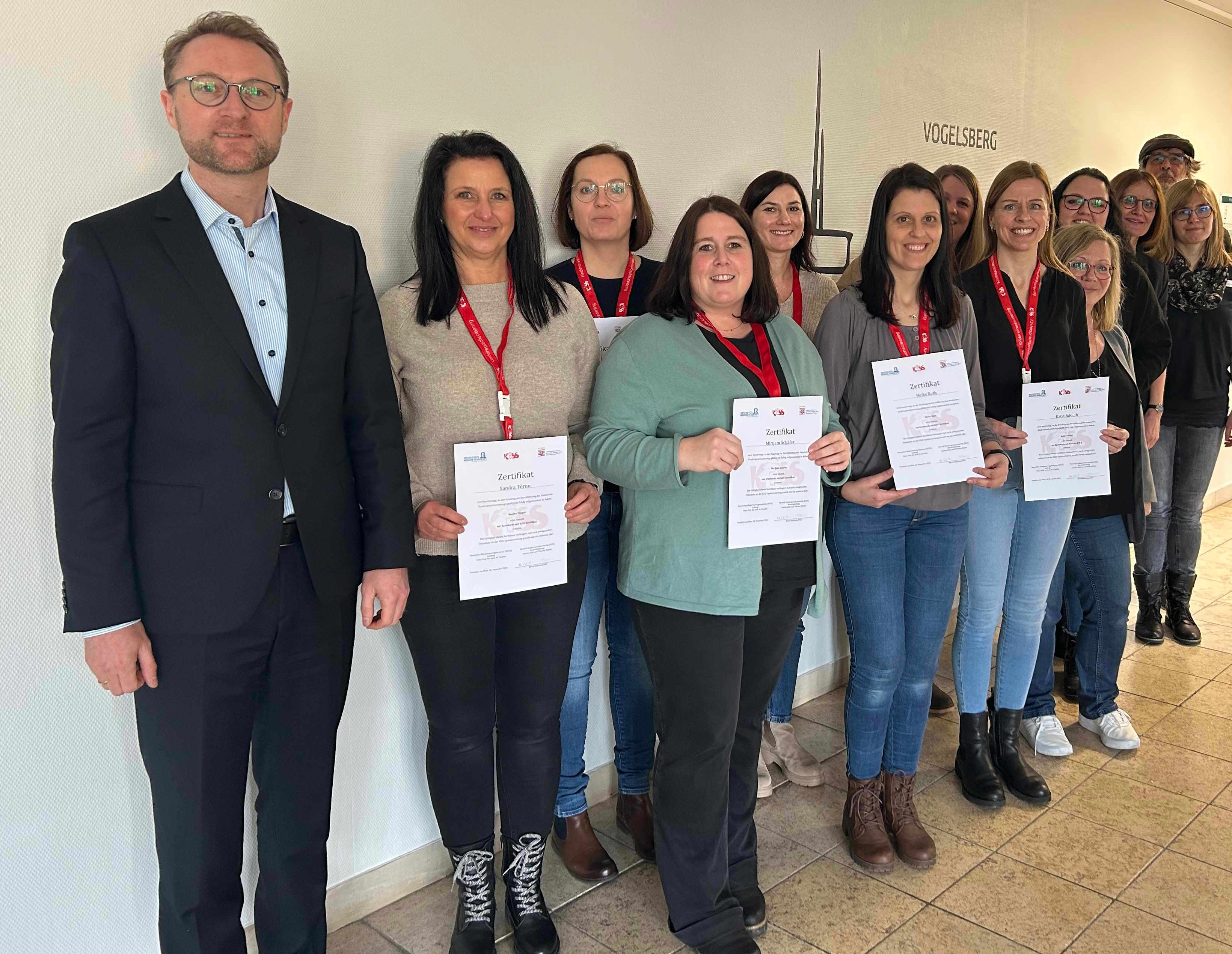 Landrat Dr. Jens Mischak (links) sowie Dr. Petra Steinker (Dritte von rechts) und Sprachheilbeauftragter Hans-Joachim Eisenträger übergeben den Erzieherinnen ihre KiSS-Zertifikate.