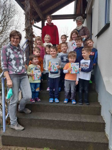 Eine Gruppe Kindergartenkinder mit drei Erzieherinnen aufgestellt zum Gruppenbild auf einer Treppe