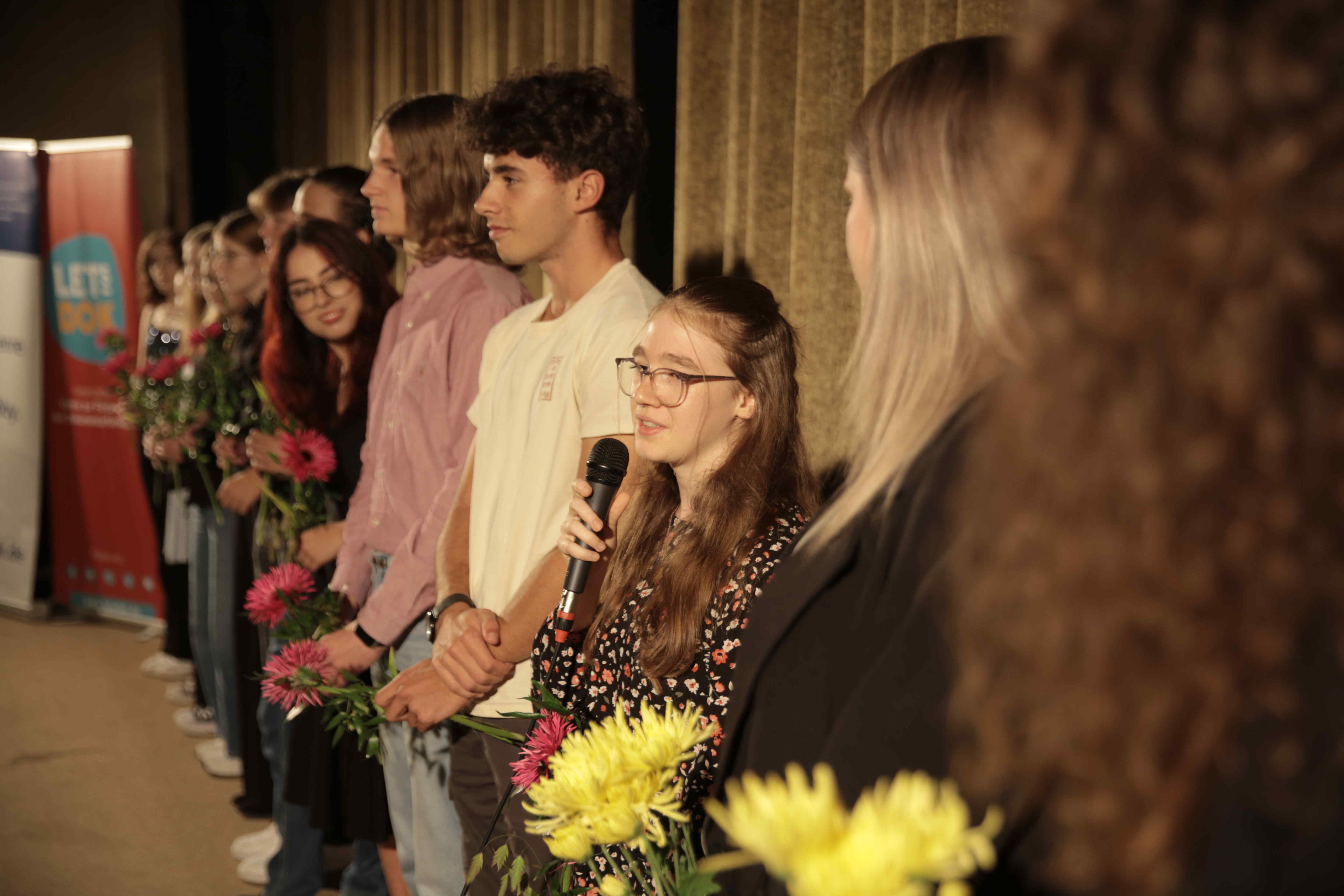 Abgeordnete des KJP stehen nach der Premiere von „Aufmachen“ Rede und Antwort. Sie haben sich in einer Reihe vor der Kino-Leinwand aufgestellt.