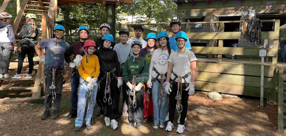 Neben ihrer parlamentarischen Arbeit nutzen die KJP-Mitglieder die freie Zeit im Kletterpark. Sie haben sich in Kletterausrüstung mit Gurten und Helmen zum Gruppenbild aufgestellt