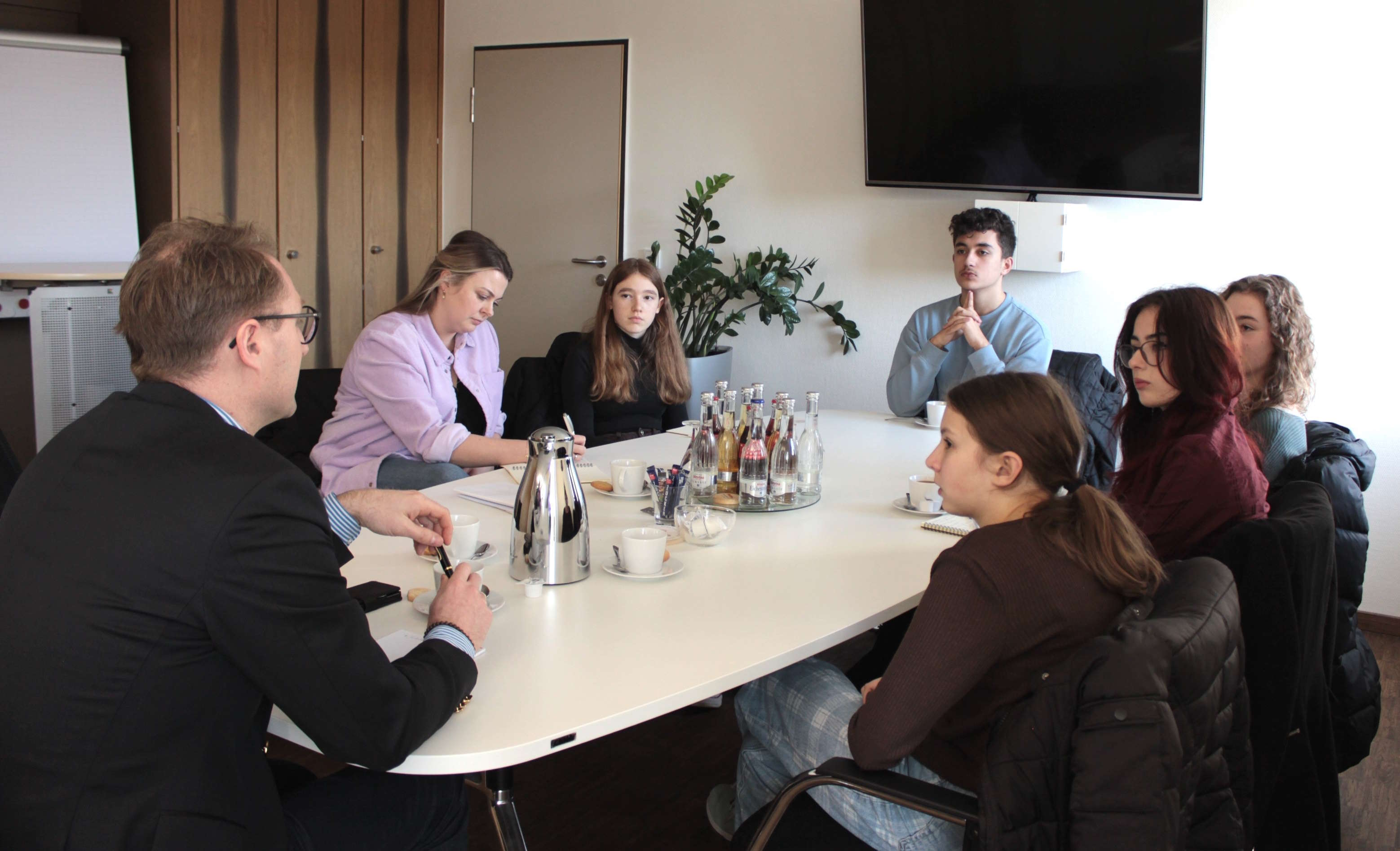 Dr. Jens Mischak im Gespräch Angelina Kuhl vom Jugendamt und den KJP-Abgeordneten Selin Volp, Armin Salavati, Amelie Theis, Johanna Faubel und Esther Arnold (im Uhrzeigersinn). 