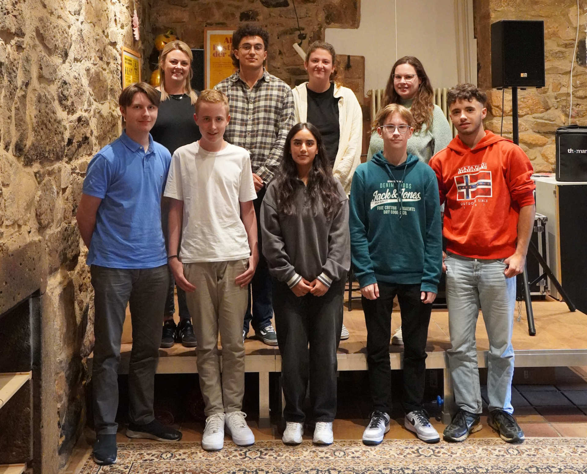 Mehrere Menschen haben sich für ein Gruppenbild aufgestellt und lächeln in die Kamera. 