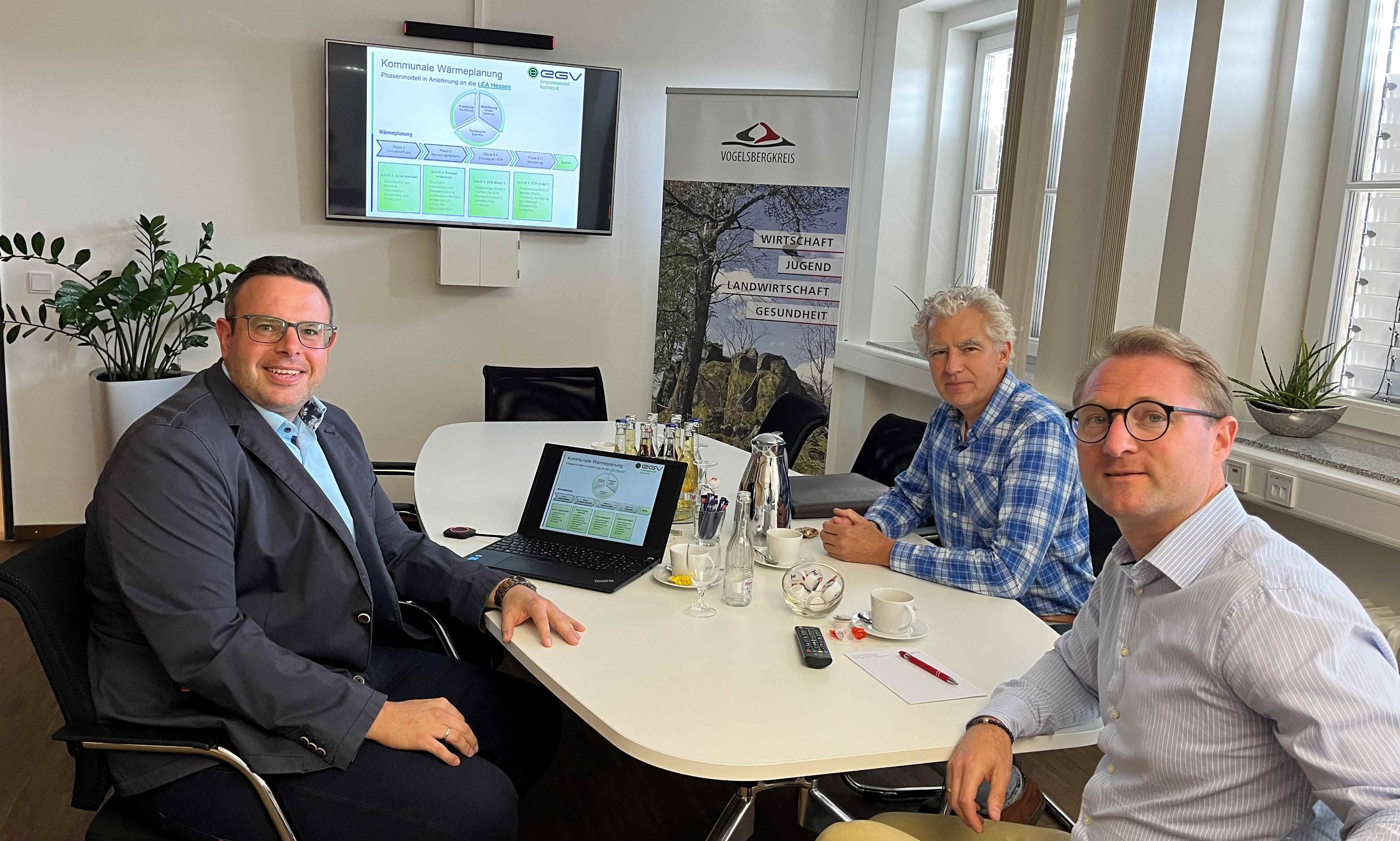 Björn Köhler (links), Erster Kreisbeigeordneter Dr. Jens Mischak (Mitte) und der Leiter der Wirtschaftsförderung der Kreisverwaltung, Lorenz Kock sitzen an einem Konferenztisch und schauen in die Kamera