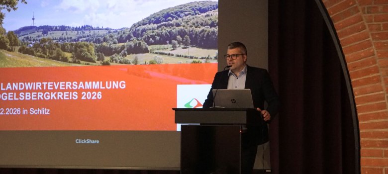 Kreislandwirt Andreas Kornmann eröffnet die Versammlung. Er steht an einem Rednerpult auf einer Bühne