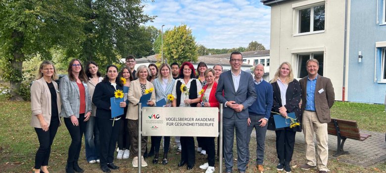 Rund 20 Personen stehen auf einer Wiese für ein Gruppenbild. Erster Kreisbeigeordneter und Sozialdezernent Patrick Krug (vierter von rechts) gratuliert gemeinsam mit Jan Klassert (dritter von rechts), Prokurist und Referent der Geschäftsführung des Kreiskrankenhauses in Alsfeld, sowie Schulleiterin Karen Heipel (links), Schulleiter Thomas Müller (rechts) und Klassenleiterin Laura Schlauch (zweite von links) den Absolventinnen und Absolventen im Krankenpflegehelfer-Kurs.