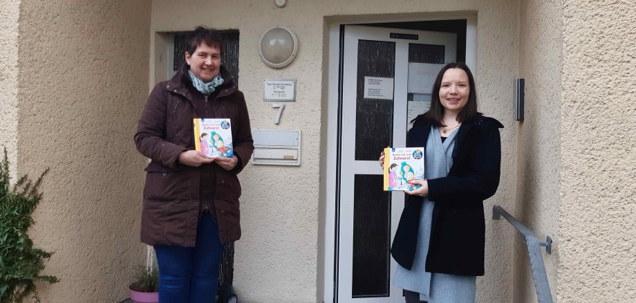 Uta Born von der Jugendzahnpflege des Vogelsbergkreises überreicht ein Buchgeschenk an Jessica Pfeiffer, Leitung der Krabbelgruppe in Schlitz 