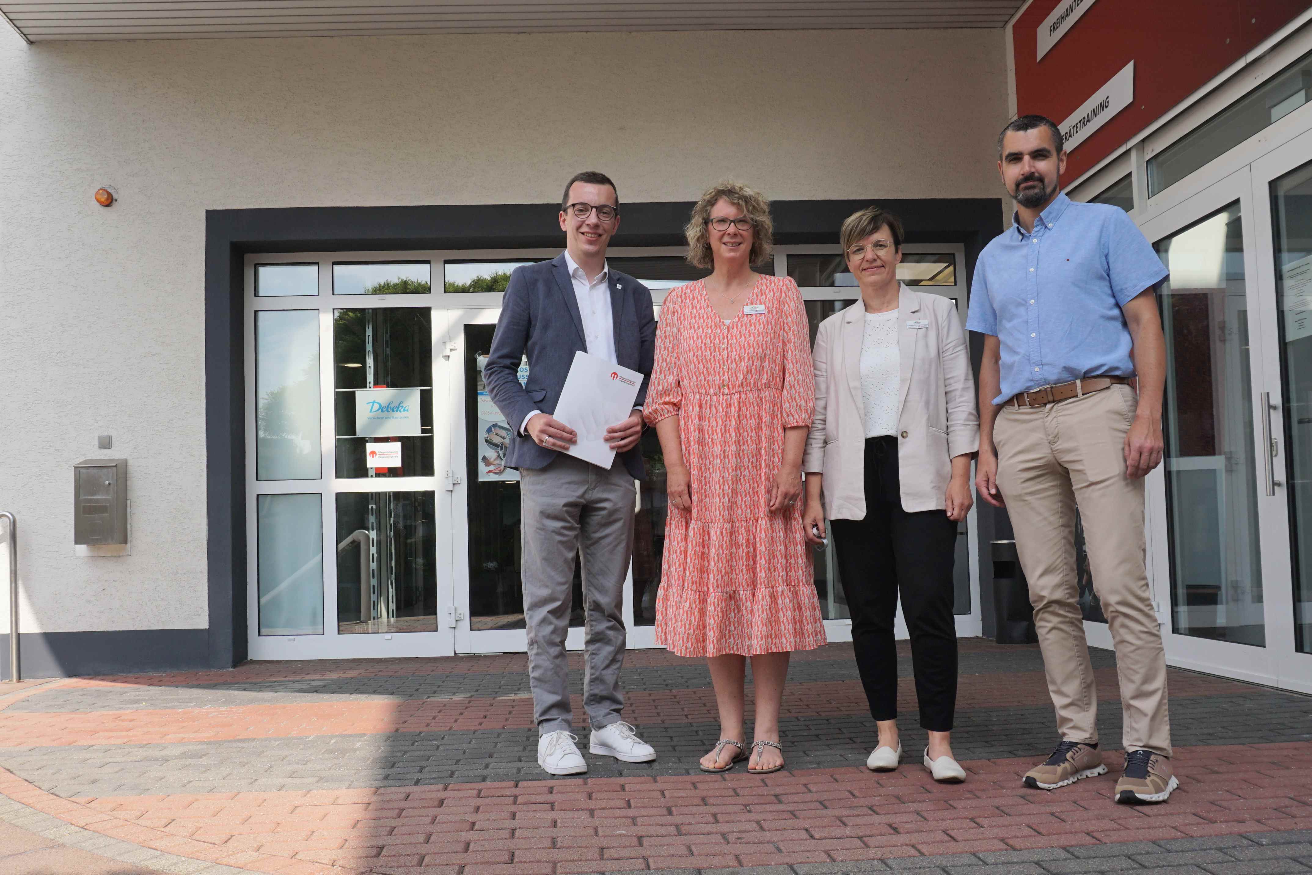 Der neue Sozialdezernent und Erste Kreisbeigeordnete Patrick Krug (links) besucht gemeinsam mit René Lippert, Leiter des Amts für Soziales und Ausländerrecht, den Alsfelder Standort des Pflegestützpunkts Vogelsberg. Claudia Vaupel (von rechts) und Sonja Reichel stellen im Rahmen des Besuchs die Besonderheiten der Arbeit vor. Sie stehen auf einer Treppe vor einer breiten weißen Eingangstür.