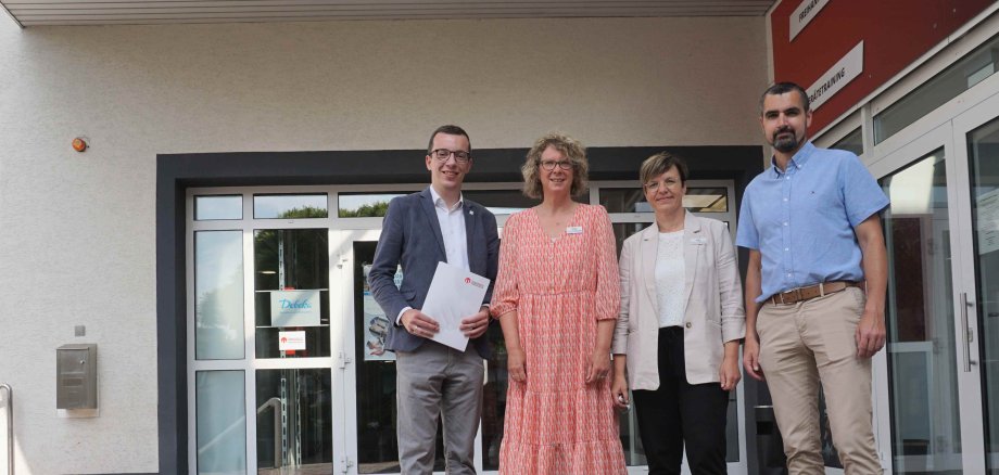 Der neue Sozialdezernent und Erste Kreisbeigeordnete Patrick Krug (links) besucht gemeinsam mit René Lippert, Leiter des Amts für Soziales und Ausländerrecht, den Alsfelder Standort des Pflegestützpunkts Vogelsberg. Claudia Vaupel (von rechts) und Sonja Reichel stellen im Rahmen des Besuchs die Besonderheiten der Arbeit vor. Sie stehen auf einer Treppe vor einer breiten weißen Eingangstür.
