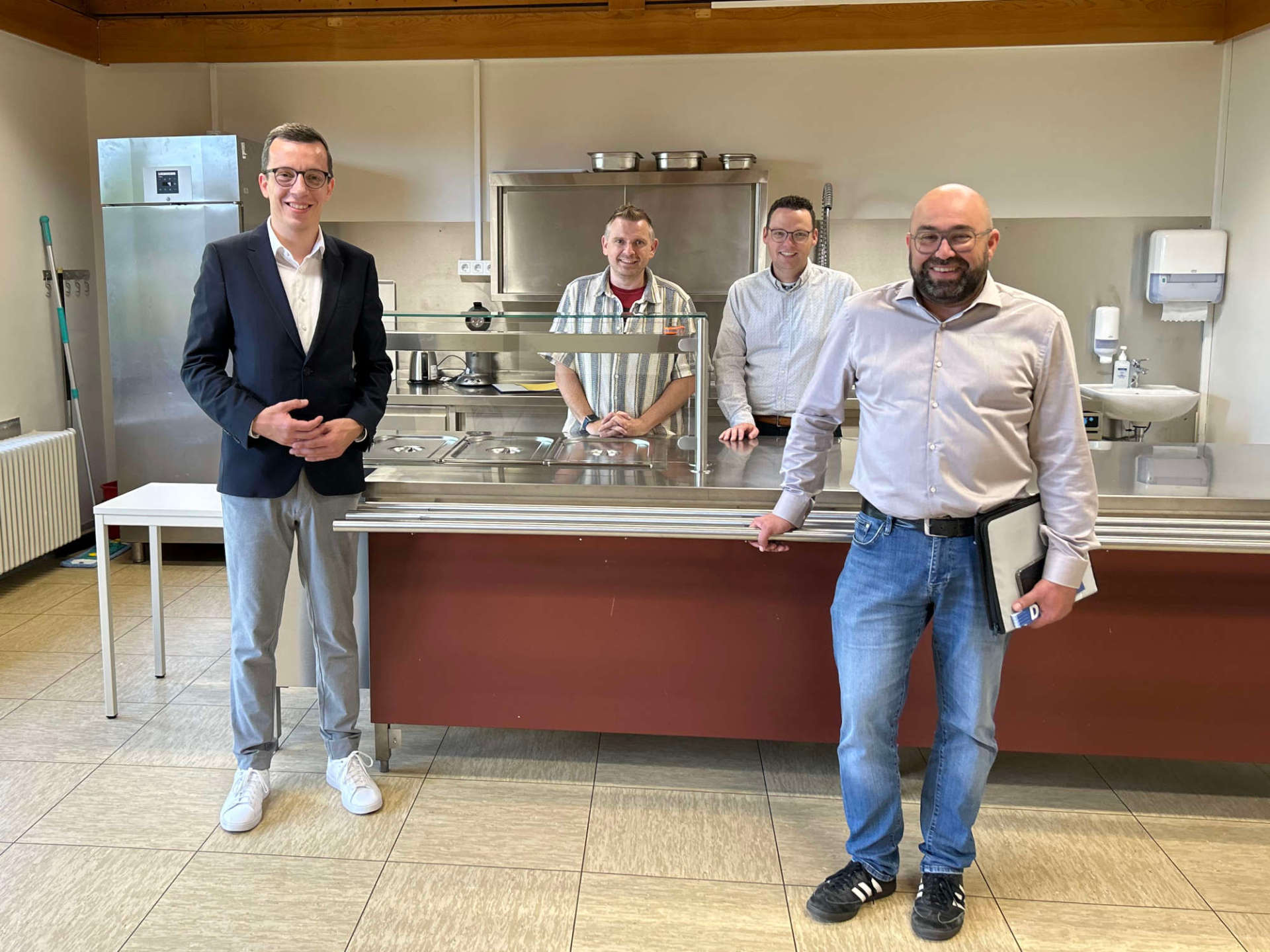 Erster Kreisbeigeordneter und Schuldezernent Patrick Krug (von links) präsentiert gemeinsam mit Schulleiter Nils Strowitzki, Matthias Röse, Leiter des Amts für Schulische Bildung und Betreuung, und Stefan Schmidt, dem Leiter des Amtes für Hochbau, Energie und Gebäudewirtschaft, die neue Essensausgabe an der Grundschule in Kirtorf.